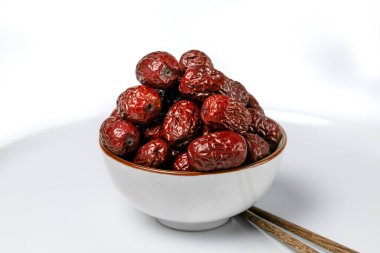 Çin yemek çubuklarıyla beyaz arka planda seramik bir fincanda kurutulmuş Çin yemekleri.