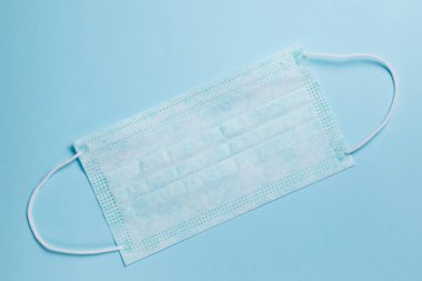 Tıbbi maske, mavi arka planda tıbbi koruyucu maske. Tek kullanımlık yüz maskesi ağız ve burnu kapatır. Sağlık ve Tıp Konsepti.