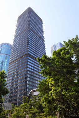 Şehirdeki yüksek binalar açık güneşli havalarda tropik yeşiller, Shenzhen, Çin, Asya