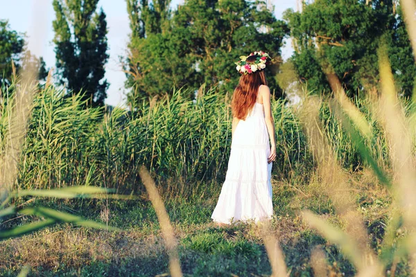 欄の花の冠を身に着けている白いドレスの立っている女性. — ストック写真