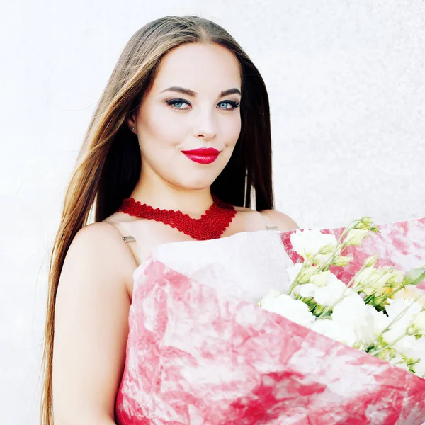 Vrouw in witte jurk met een boeket van witte bloemen, verpakt in roze papier. — Stockfoto