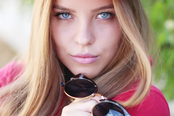 Atraente jovem mulher segurando óculos de sol — Fotografia de Stock