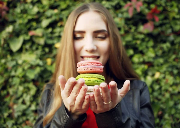 Atractiva mujer sosteniendo macarrones en las manos — Foto de Stock