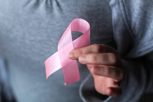Sağlık ve tıp konsepti - kadınların elleri pembe meme kanseri farkındalığı kurdelesi tutuyor
