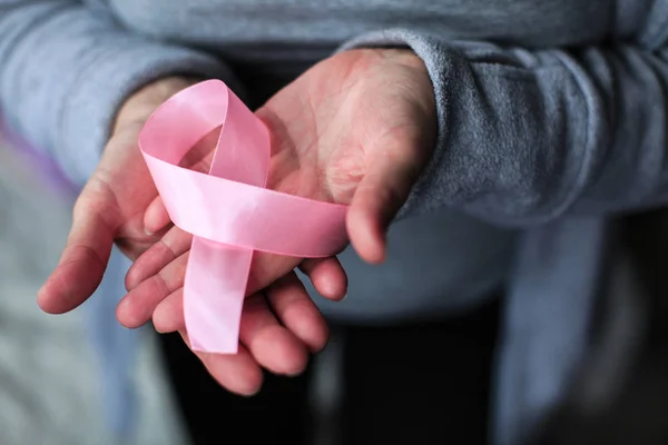 Sağlık ve tıp konsepti - kadınların elleri pembe meme kanseri farkındalığı kurdelesi tutuyor