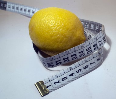  Beyaz arka planda santimetre uzunluğunda bir kurdeleyle çevrili bir limon..