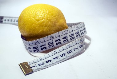  Beyaz arka planda santimetre uzunluğunda bir kurdeleyle çevrili bir limon..