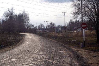 Uyarı işareti olan eğri asfalt yol.