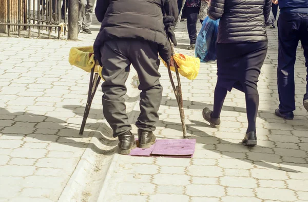 A disabled man with crutches on his side and boxes on his hands in the center of the market.