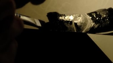 Bir insan bir kağıt parçasına siyah boya çizer.