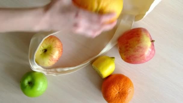 Main empile des fruits dans un shopper — Video