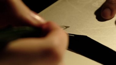 Bir insan bir kağıt parçasına siyah boya çizer.