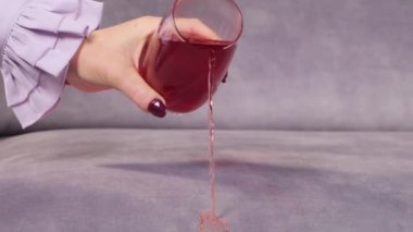 Meyve suyu bir bardaktan kanepeye dökülür.