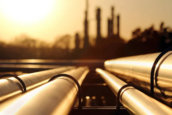 Золотой закат на нефтеперерабатывающем заводе с трубопроводной системой — стоковое фото