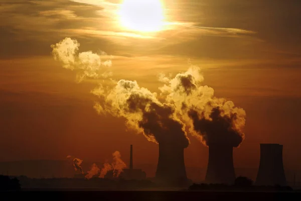 Puesta de sol sobre una central nuclear humeante — Foto de Stock