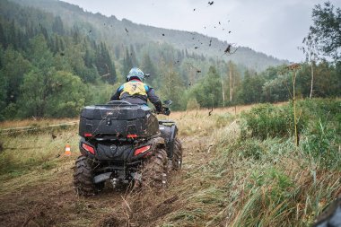quad binici bir çamurlu orman iz üzerinde atlama.