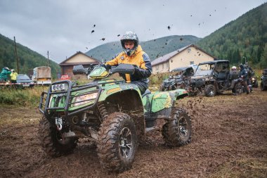 quad binici bir çamurlu orman iz üzerinde atlama.