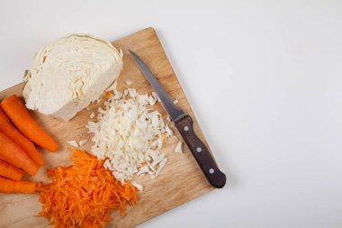 Çiğ havuç ve lahana ve bir bıçak üzerinde beyaz bir arka plan kesme