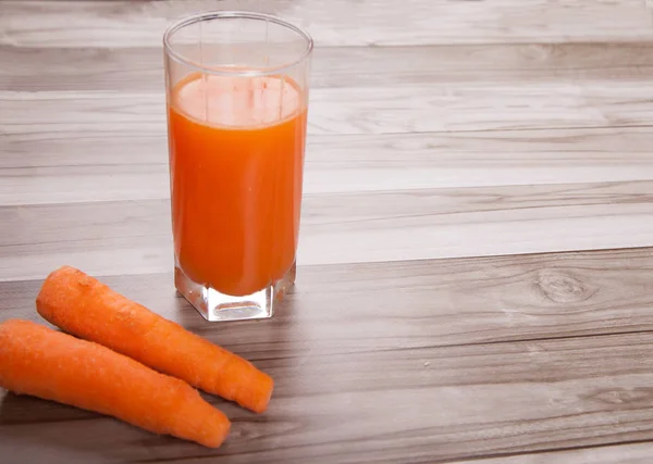 Carrots raw and carrot juice on a wooden background — Stock Photo, Image