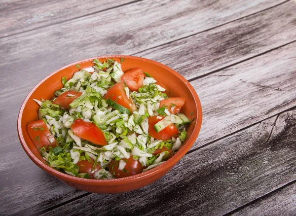 Frischer Salat aus Tomaten, Gurken und Kohl liegt auf einem Holztisch. — Stockfoto