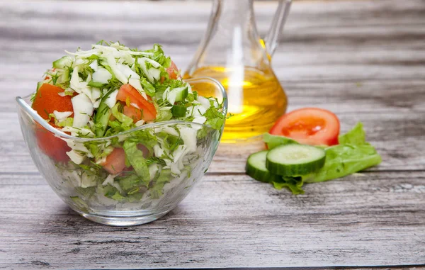 Fresh salad and vegetable oil stand on a wooden table
