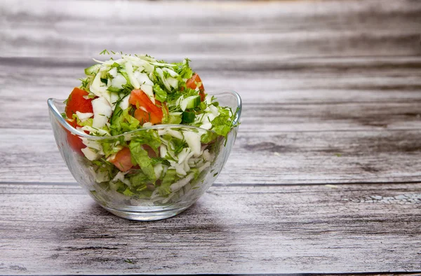 Domates salatası bir cam kabın içinde ahşap bir masa üzerinde duran