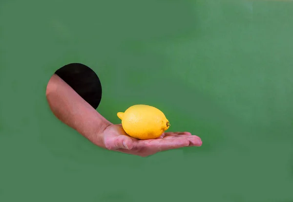 Мужская рука держит лимон через отверстие в бумаге — стоковое фото