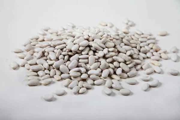 White raw beans sprinkled on a white background. — Stock Photo, Image