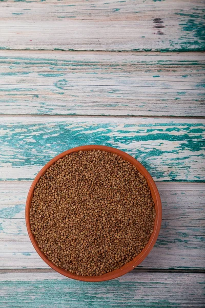 Raw buckwheat in a clay cup on a blue wooden background. Copy spaes. vertical — Stock Photo, Image