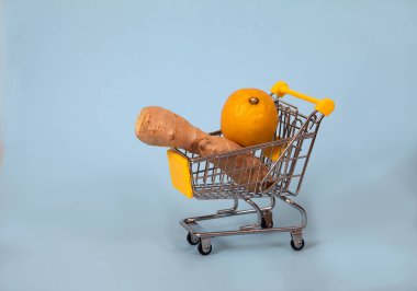 Zencefil ve limon mavi arka planda süpermarket arabasının içinde yatıyor. Sağlıklı yiyecekler. Sağlığa. Vitaminler. covyd 19. Kopyalama maçları