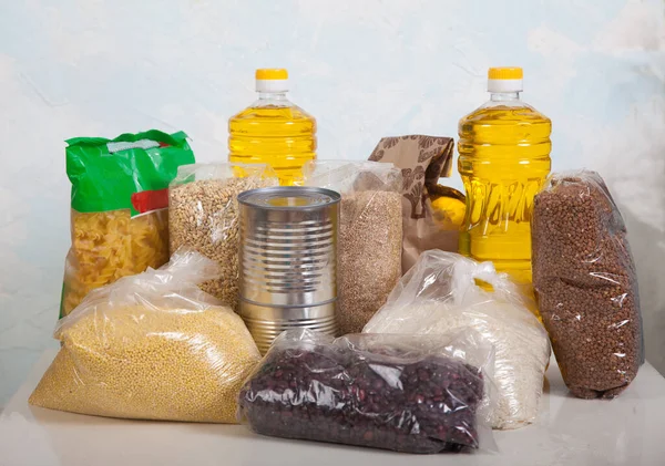 Mısır gevreği, baklagil, makarna, konserve yiyecek ve sebze yağından hafif bir arka planda bir set ürün. Yardım edin! Hayırseverlik. Sosyal.