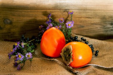 Olgun hurma ve rustik arka plan üzerinde çiçekler