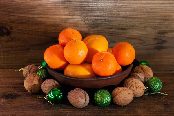 Mandarinky, ořechy, Vánoční ozdoby na dřevěné pozadí — Stock fotografie