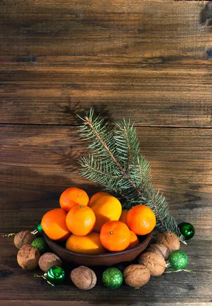 Tangerines in a bowl, nuts, fir-tree branch — Stock Photo, Image