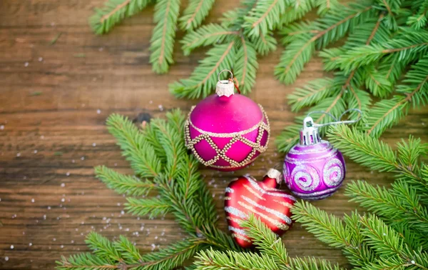 Fir branch with glass balls on wooden background — Stock Photo, Image