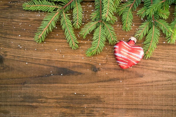 Ramo de abeto e coração decorativo no fundo de madeira — Fotografia de Stock