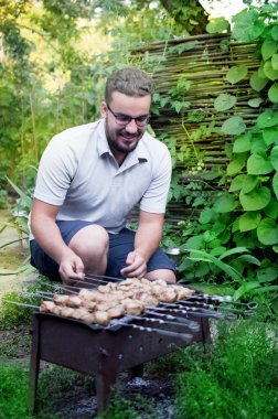 Adam bahçede barbekü hazırlıyor.