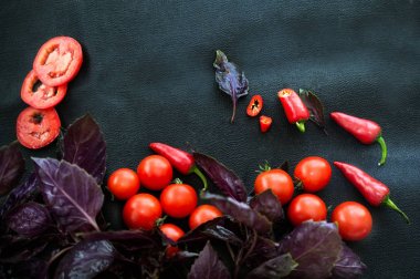 Fesleğen, kırmızı acı biber ve karanlık bir arka plan üzerinde olgun domates