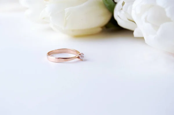 Engraved golden ring on light background and white flowers — Stock Photo, Image