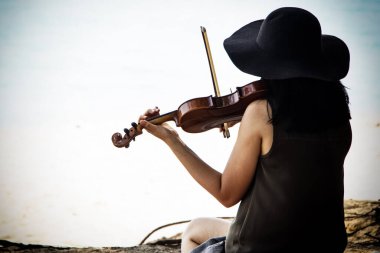 Plajda keman çalan kadının soyut sanat tasarımı arka planı, dinlenmek için, bulanık ışık etrafında