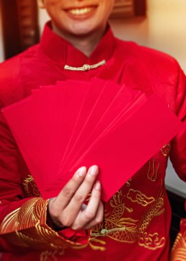 Kırmızı zarfın seçici odak noktasında insan eli vardı. Bulanık ışık vardı.