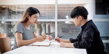 İki genç proje hakkında konuşuyor, birlikte çalışıyorlar, toplantı odasında, bulanık ışık altında..