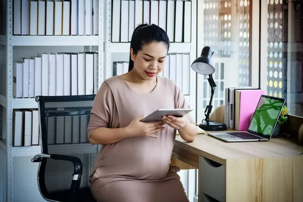 The pregnant woman working with serious feeling,busy time,at office,blurry light around