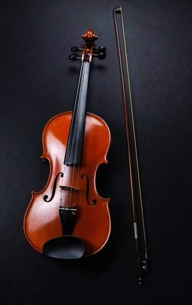 木のバイオリンと弓は黒いキャンバスの背景に置かれています — ストック写真