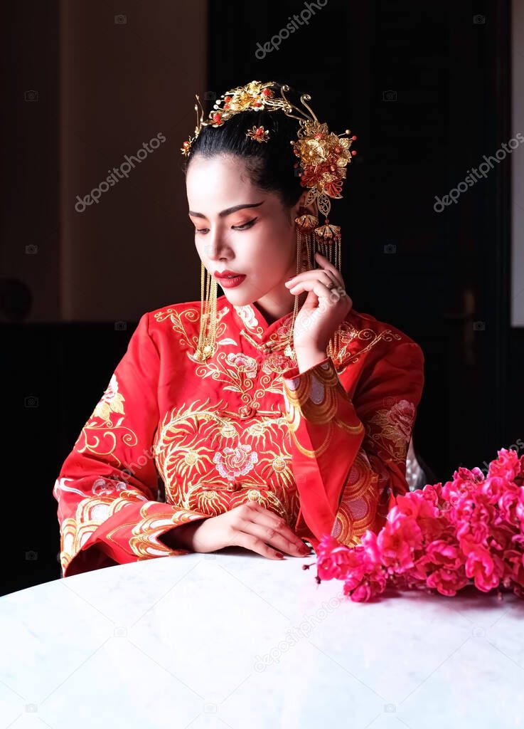 The beautiful woman wearing red suit,turn face down,,looking her hand,portrait of model posing on chinese New year festival