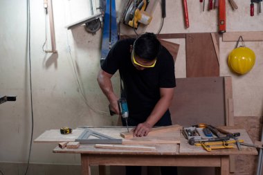 Koruyucu gözlük takan yakışıklı adam, fabrikada ahşap işi yapan, el yapımı tasarım yapan, marangoz.