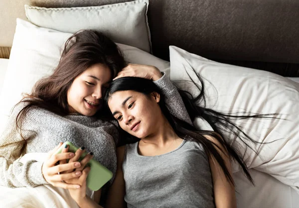 Two Beautiful Women Laying Bed Looking Blurred Mobile Phone Together — Stock Photo, Image