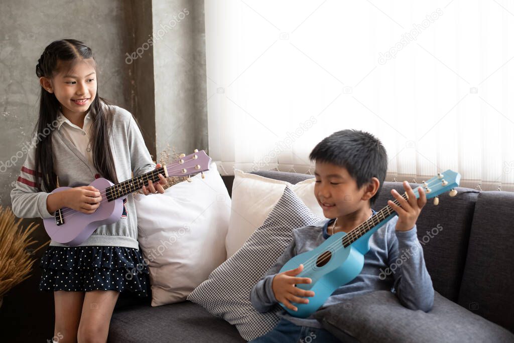 The visually impaired boy playing ukulele on sofa with his friend,at home studio,blurry light around