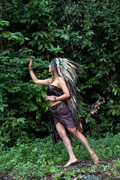 Woman wearing headdress feathers of birds. raise to reach up in the air,portrait of model posing,Jungle in forest,blurry light around