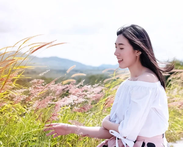 Die Schöne Frau Die Neben Grasblumen Steht Mit Lächeln Und — Stockfoto